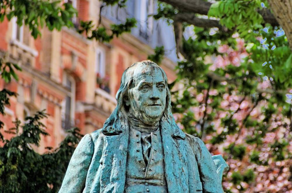 A tarnished bronze statue of Benjamin Franklin