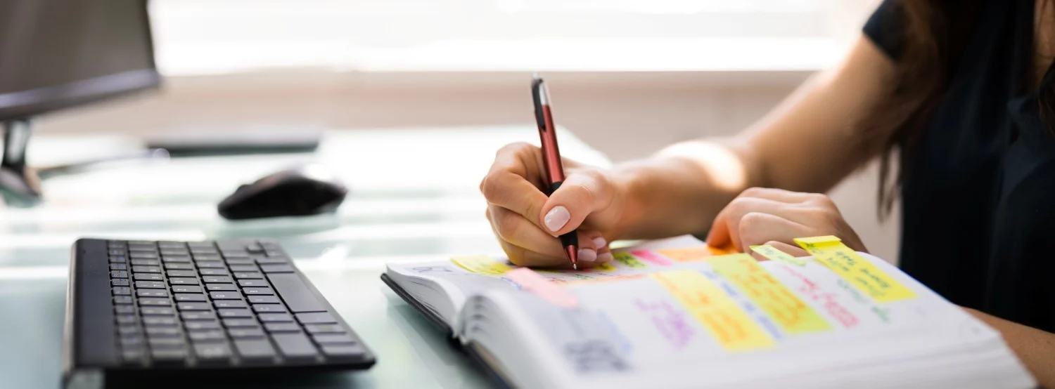 A woman writing in a monthly planner