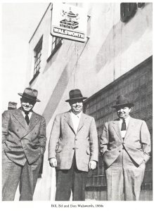 Bill, Ed and the first Don Walsworth, wearing suits, stand in front of Walsworth offices in the 1950s