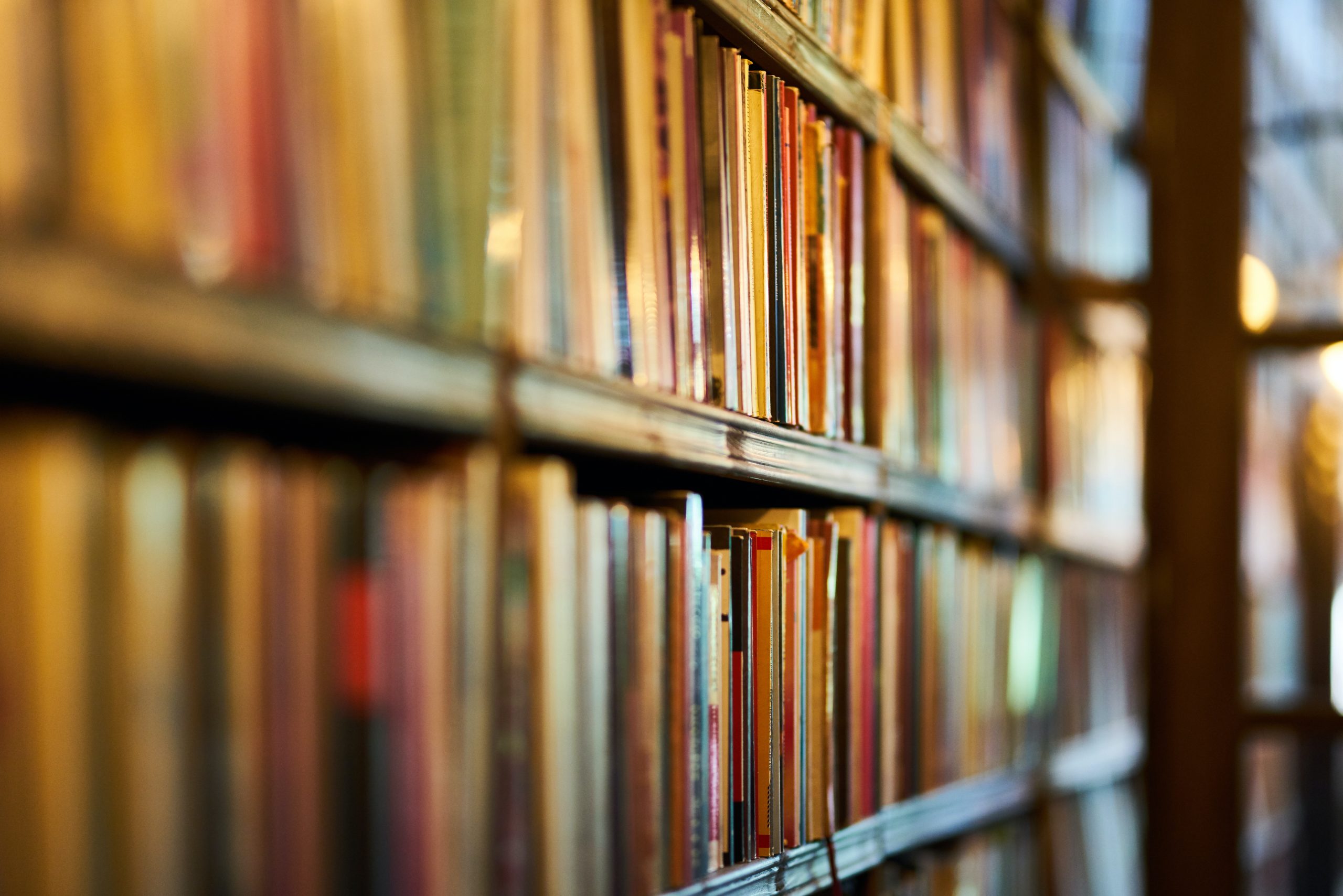 A shallow depth of field shot of books on a bookshelf taken from a side angle.