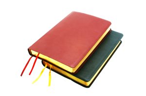 stack of two sewn leather bound books with ribbon bookmarks and gold foil edge treatment.