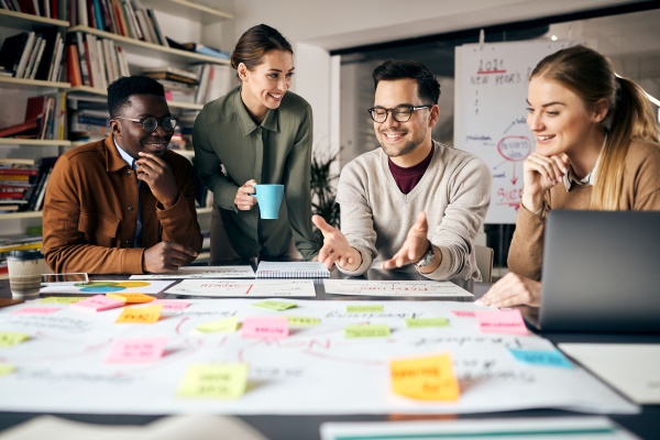 Young, smiling professionals gathered around a table collaborating on a project