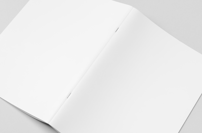 A blank magazine folded open to display saddle stitching