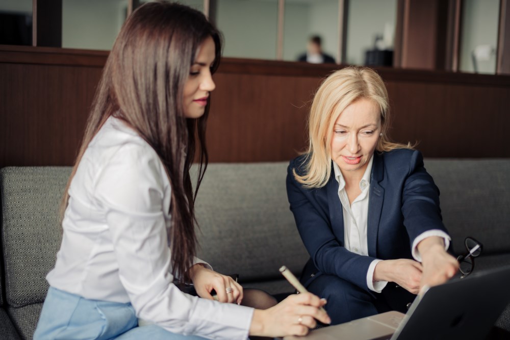 Two professionally-dressed women collaborating on a project on a tablet
