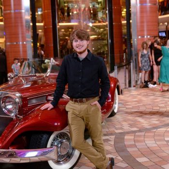 Cayden Pliler standing by a vintage car