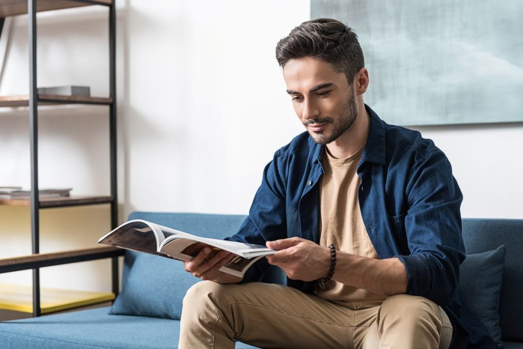 A man sitting on a couch reading a magazine