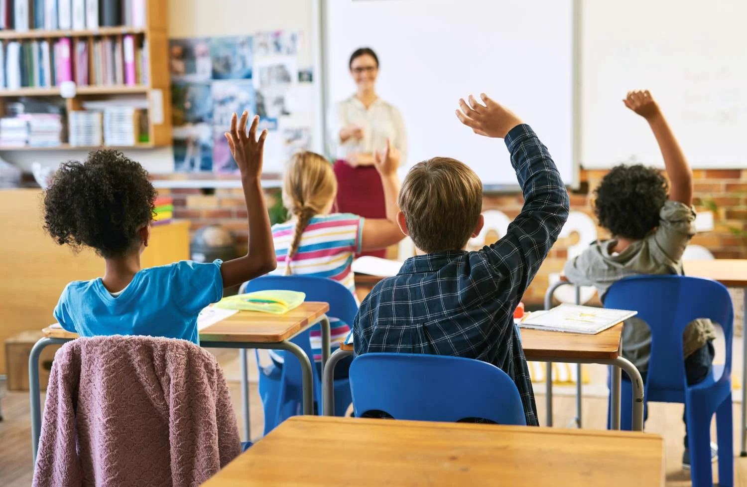 Children raising their hands in class