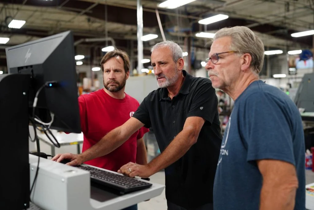 Three Walsworth employees working on a printer