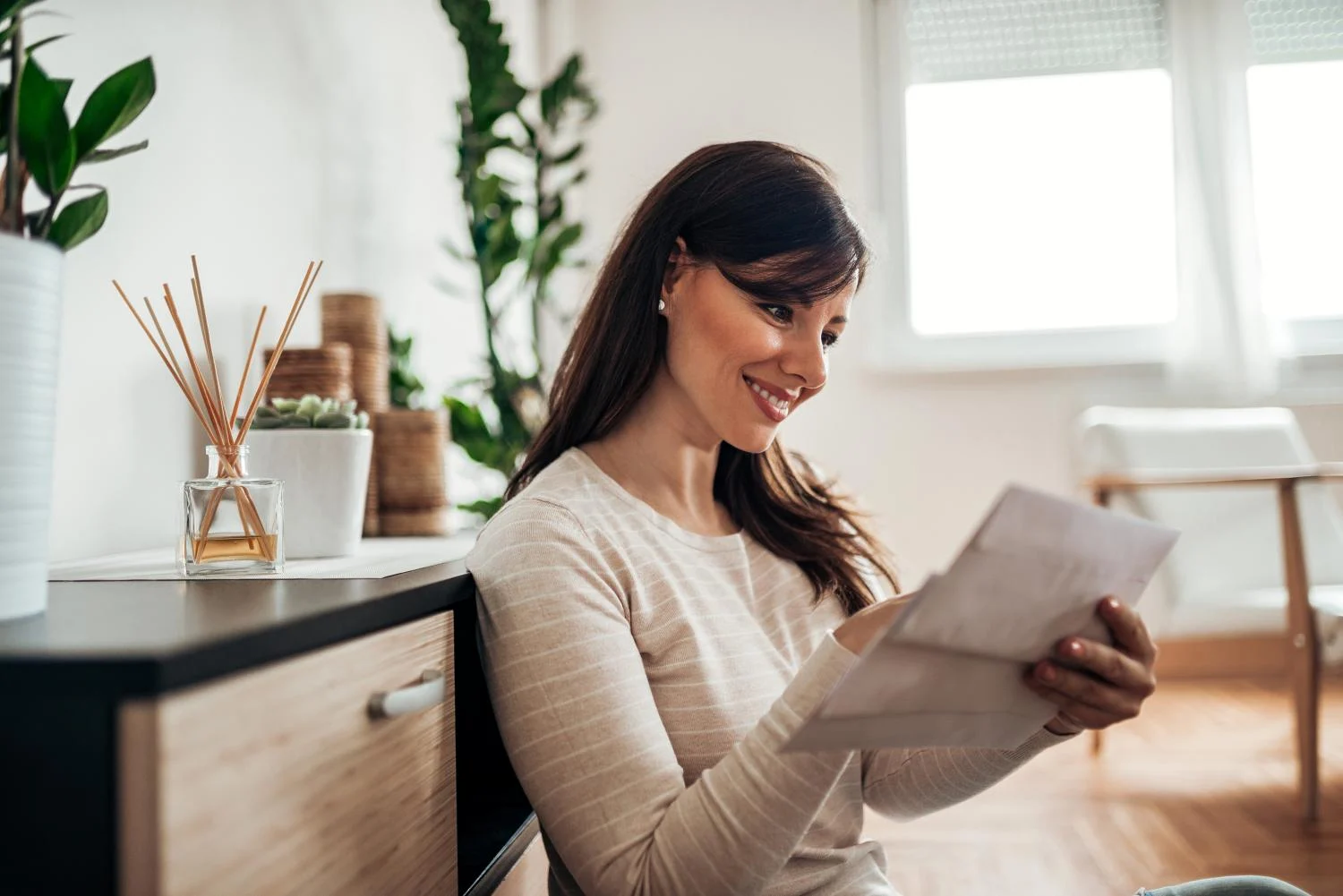 A woman smiling reading her mail