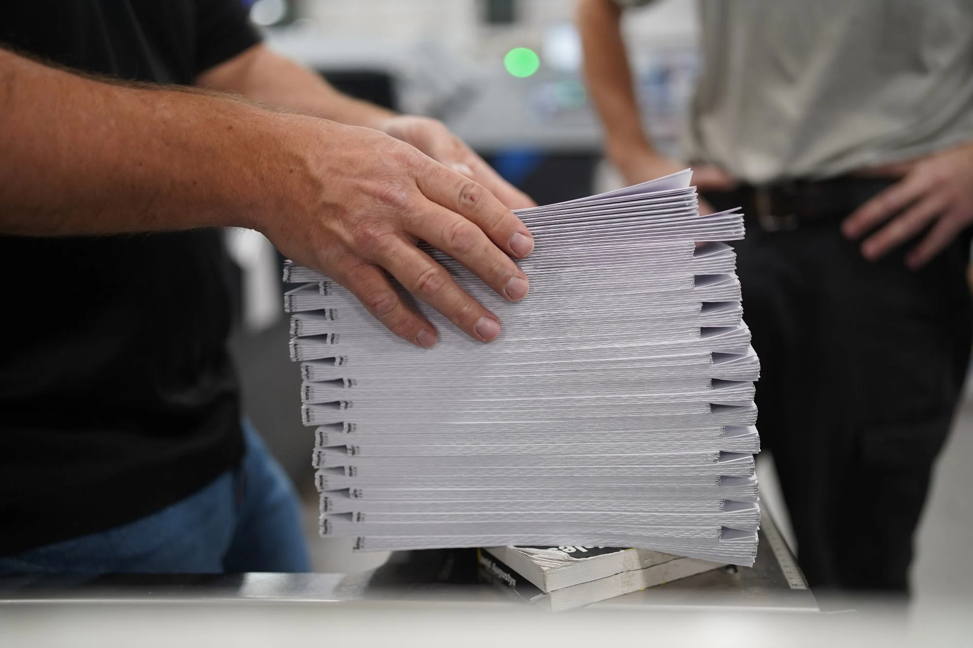 Two workers at Walsworth -- Eau Claire handle a stack of signatures
